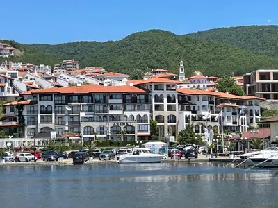 a large building with cars parked in a marina at Apartment Marina Dinevi View in Sveti Vlas