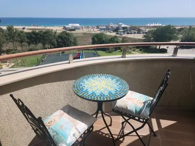 a table and chairs on a balcony with a view of the ocean at Golden Sunrise in Shkorpilovtsi
