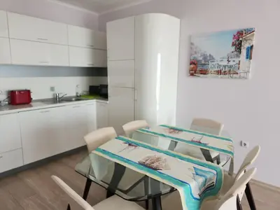 a kitchen with white cabinets and a table and chairs at Golden Sunrise in Shkorpilovtsi