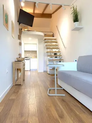 a living room with a couch and a spiral staircase at Апартамент за гости in Varna City