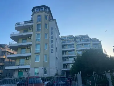 a tall building with cars parked in front of it at Комплекс Бриз / Breeze Complex Apartments in Sunny Beach