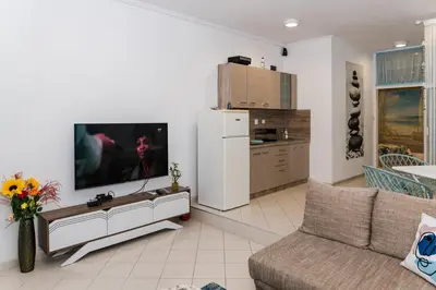 a living room with a couch and a tv on a wall at Луксозен апартамент Далия in Varna City