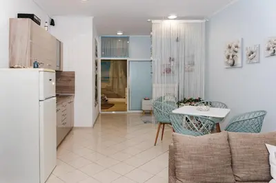 a kitchen and a living room with a table and a refrigerator at Луксозен апартамент Далия in Varna City