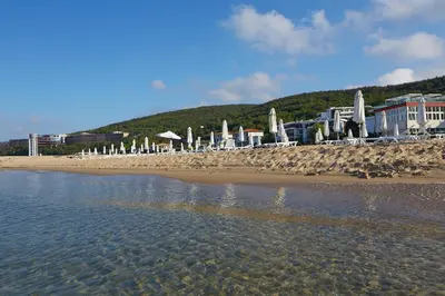 a beach with umbrellas and buildings and the water at Hotel Amore Beach - All Inclusive in Elenite