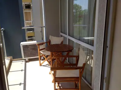 a balcony with two chairs and a table and a window at Sun City Apartments in Sunny Beach