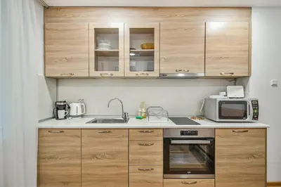 a kitchen with wooden cabinets and a microwave at Hideout in heart of Varna with WiFi in Varna City