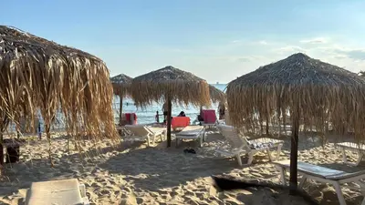 a group of chairs and straw umbrellas on a beach at Lazur Sea View, Sveti Vlas Beach in Sveti Vlas