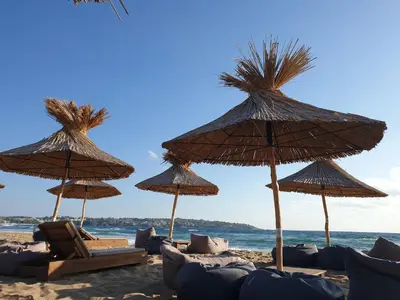 a group of straw umbrellas and chairs on a beach at Smokinia Sunrise - Kavatsi Beach, Sozopol in Sozopol