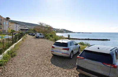two cars parked on a gravel road near the water at Royal Bay-I Seaview Apartment in Sveti Vlas