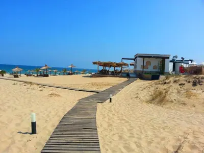 a wooden pathway on a beach with umbrellas at Menada Green Hills Apartments in Sozopol