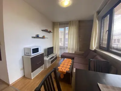 a living room with a couch and a tv at Apartments Amara Sunny Beach in Sunny Beach