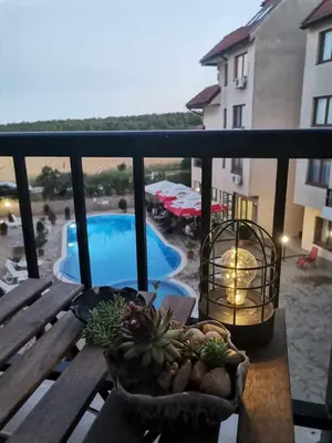 a table with plants on a balcony with a pool at Апартамент в Oasis beach Kamchia - Лунна пътека in Dolen Bliznak