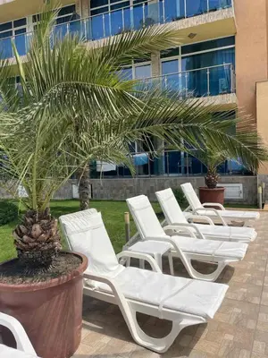a row of white lounge chairs in front of a building at Apart hotel Gallery B in Sunny Beach