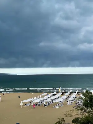 a beach with many white chairs and umbrellas at Apart hotel Gallery B in Sunny Beach