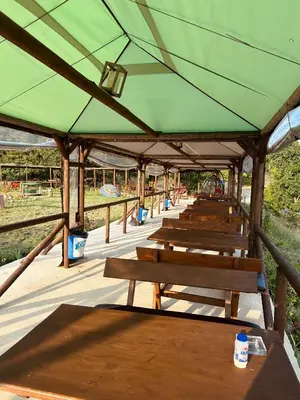 a row of wooden benches under a green roof at Комплекс Тополица -The beautiful view in Aytos