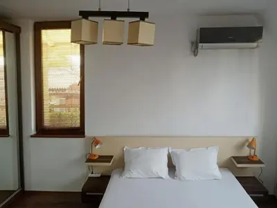 a bedroom with a large white bed and a tv at Голям апартамент с прекрасна гледка кьм морето in Ravda
