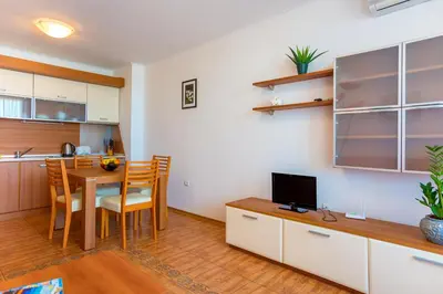 a kitchen and dining room with a table and a television at Apartment complex Mirage of Nessebar in Nesebar