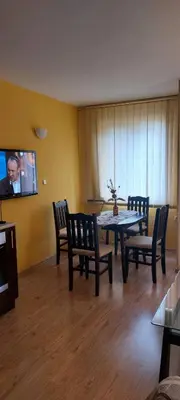 a dining room with a table and chairs and a tv at Илеа апартамент in Burgas City