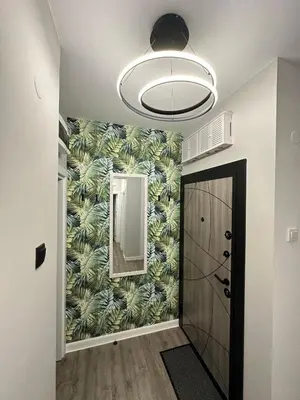 a hallway with a door and a wall with a leafy wallpaper at Varna Cathedral Boutique Apartment in Varna City
