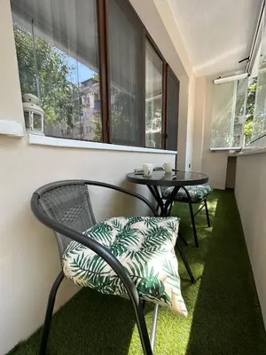 a chair and a table in a room with windows at Varna Cathedral Boutique Apartment in Varna City