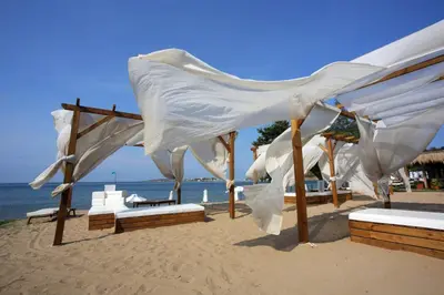 a group of white umbrellas on the beach at Санта Марина-Сладка къща in Sozopol