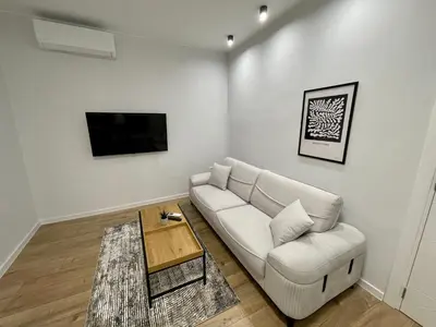 a living room with a white couch and a tv at Vanquish Central Apartment in Varna City