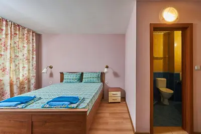 a bedroom with a bed with blue pillows and a bathroom at Family Hotel Electra in Pomorie