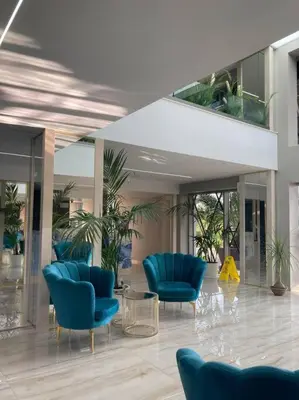 a lobby with blue chairs and plants in a building at Apartament Harmony in Sunny Beach