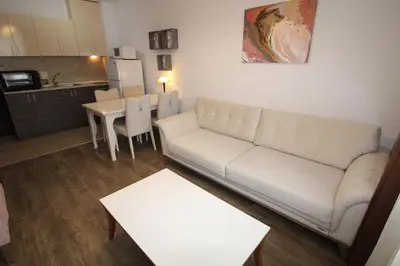a living room with a white couch and a kitchen at Villa Aria - Menada Apartments in Sunny Beach