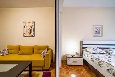 a bedroom with a yellow couch next to a bed at Primorski 2bdrm Central Apartment in Varna City