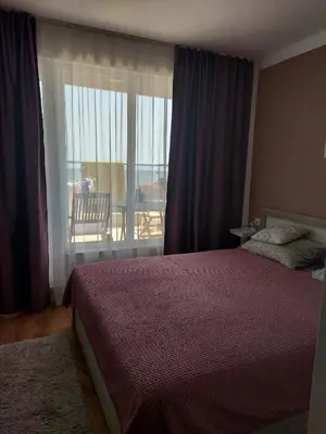 a bedroom with a bed and a view of a balcony at Прекраснные апартаменты с панорамным видом на море in Byala