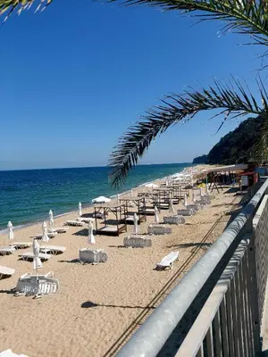 a beach with chairs and umbrellas and the ocean at Прекраснные апартаменты с панорамным видом на море in Byala