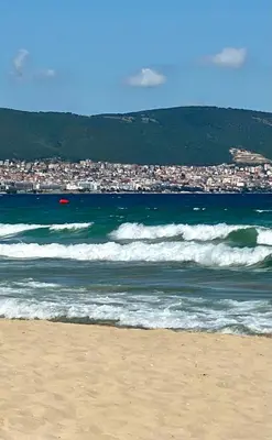 a beach with waves and a city in the background at Penthouse Happy Moments 3 in Sunny Beach