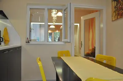 a dining room with a table and yellow chairs at Arlequin Apartment in Varna City
