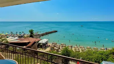 a beach with umbrellas and people in the water at Beachfront Havana in Sveti Vlas