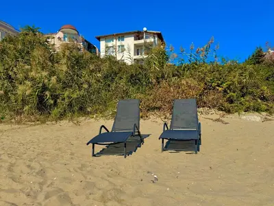 two beach chairs sitting on the sand on a beach at Beachfront Havana in Sveti Vlas