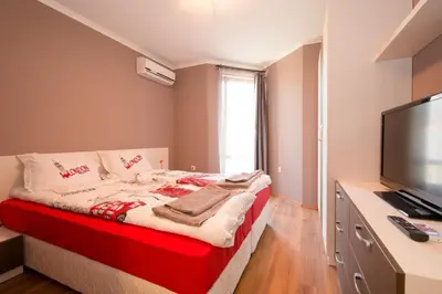 a bedroom with a bed and a flat screen tv at Holiday Village Lozenets in Lozenets