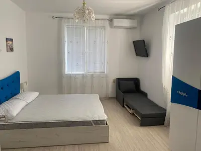 a bedroom with a bed and a couch and a window at Bluemoon-Apartment with Parking in Burgas City