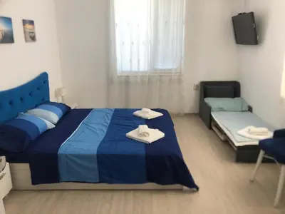 a bedroom with a blue bed and a couch at Bluemoon-Apartment with Parking in Burgas City