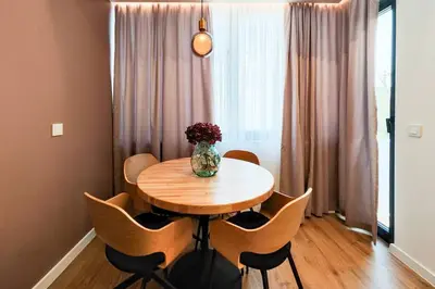 a wooden table with chairs and a vase of flowers on it at OPAL Beachfront Apartment in Varna City