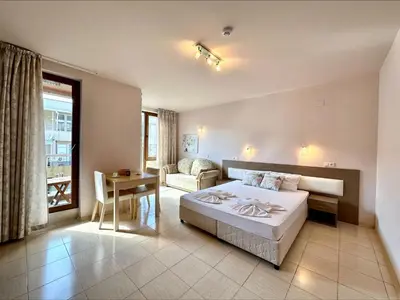 a bedroom with a bed and a couch and a table at Pomorie Bay - Menada Apatments in Pomorie