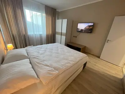 a large white bed in a room with a tv at City Center Apartment 2 in Varna City