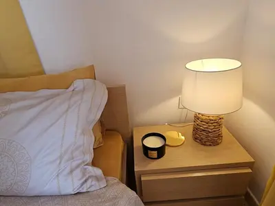 a lamp on a night stand next to a bed at Квартира с потрясающим видом in Sveti Vlas