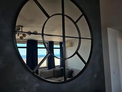 a circular mirror in a living room with a window at Квартира с потрясающим видом in Sveti Vlas