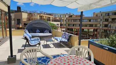 a patio with chairs and a bed on a balcony at Таунхаус с шикарной террасой in Sveti Vlas
