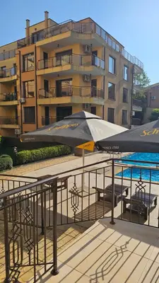 a large umbrella on a balcony next to a building at Таунхаус с шикарной террасой in Sveti Vlas