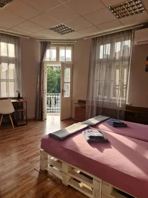 a bedroom with a large bed in a room with windows at Lambo's Corner Varna - Guest Rooms in Varna City