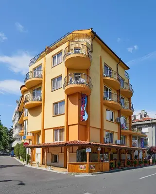 a tall yellow building with balconies on a street at Peneka Hotel in Pomorie