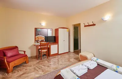 a bedroom with a bed and a desk and a chair at Peneka Hotel in Pomorie