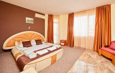 a bedroom with a large bed and a red chair at Peneka Hotel in Pomorie